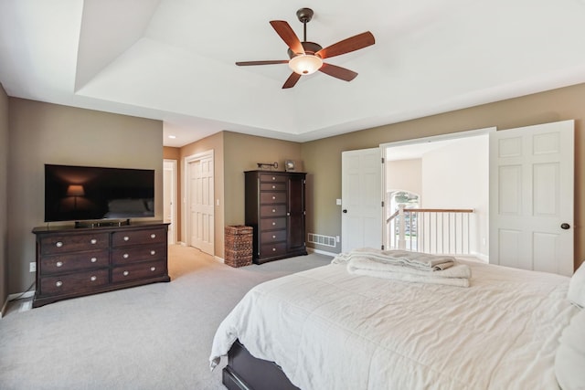 bedroom featuring visible vents, a tray ceiling, baseboards, and light colored carpet