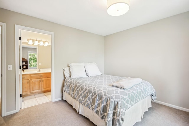 bedroom featuring a sink, baseboards, connected bathroom, and light colored carpet