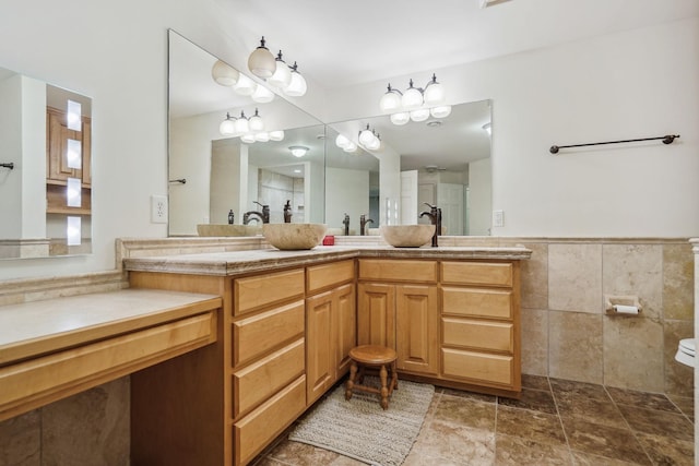 full bath featuring tile walls, an enclosed shower, stone finish floor, wainscoting, and vanity