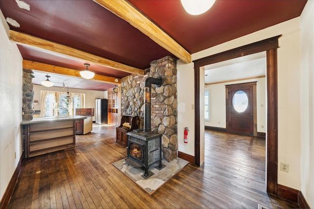 living room with beam ceiling, a wood stove, and dark hardwood / wood-style flooring