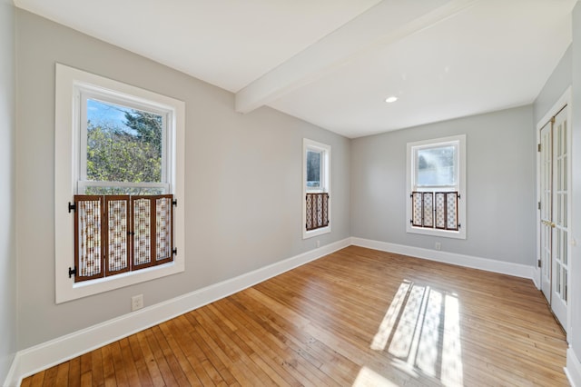 spare room featuring light hardwood / wood-style flooring and beamed ceiling