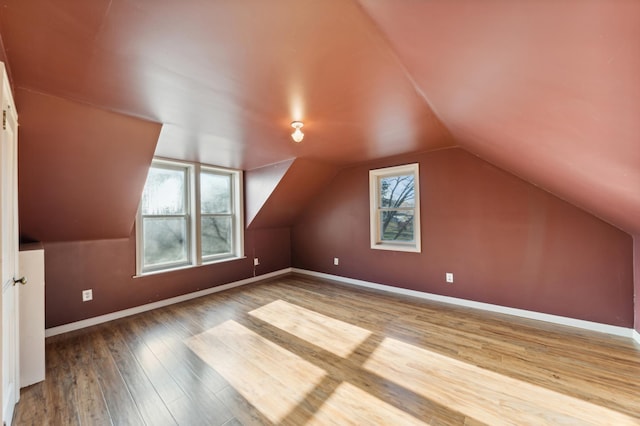 additional living space featuring lofted ceiling, hardwood / wood-style flooring, and a healthy amount of sunlight