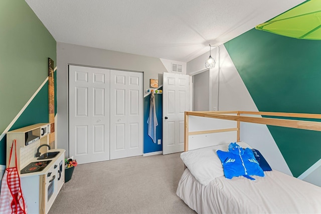 carpeted bedroom featuring sink, a closet, and a textured ceiling