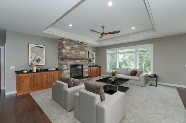 living room featuring a fireplace, hardwood / wood-style flooring, ceiling fan, and a tray ceiling