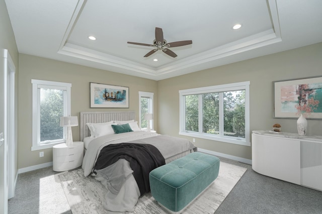 bedroom with light colored carpet, a raised ceiling, multiple windows, and ceiling fan