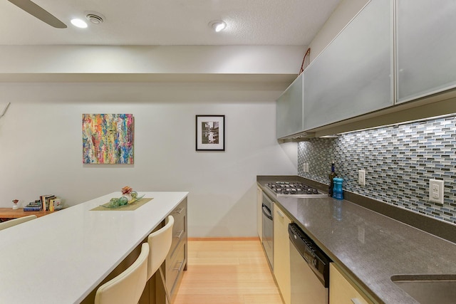 kitchen with light hardwood / wood-style flooring, backsplash, and stainless steel appliances