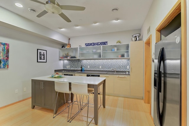 kitchen with a kitchen breakfast bar, stainless steel fridge, light hardwood / wood-style flooring, and tasteful backsplash