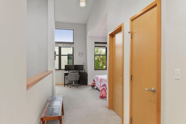 hall featuring light colored carpet and lofted ceiling