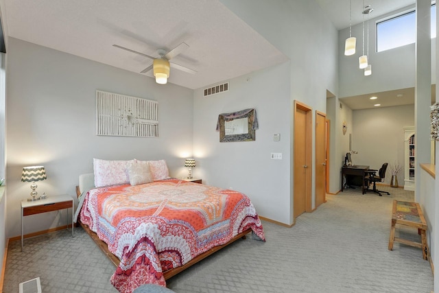 carpeted bedroom featuring a towering ceiling and ceiling fan