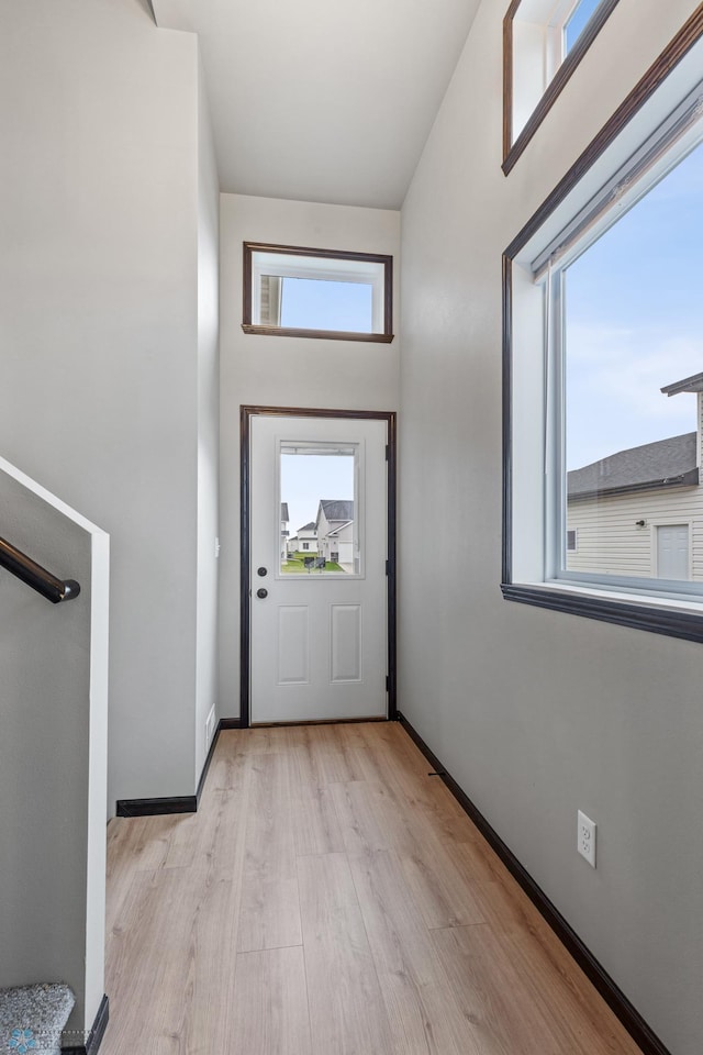 doorway to outside with a towering ceiling and light hardwood / wood-style flooring