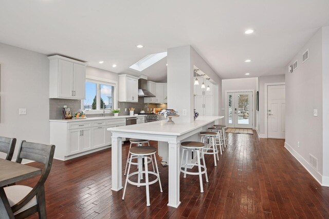 kitchen with backsplash, a skylight, a kitchen breakfast bar, and white cabinets