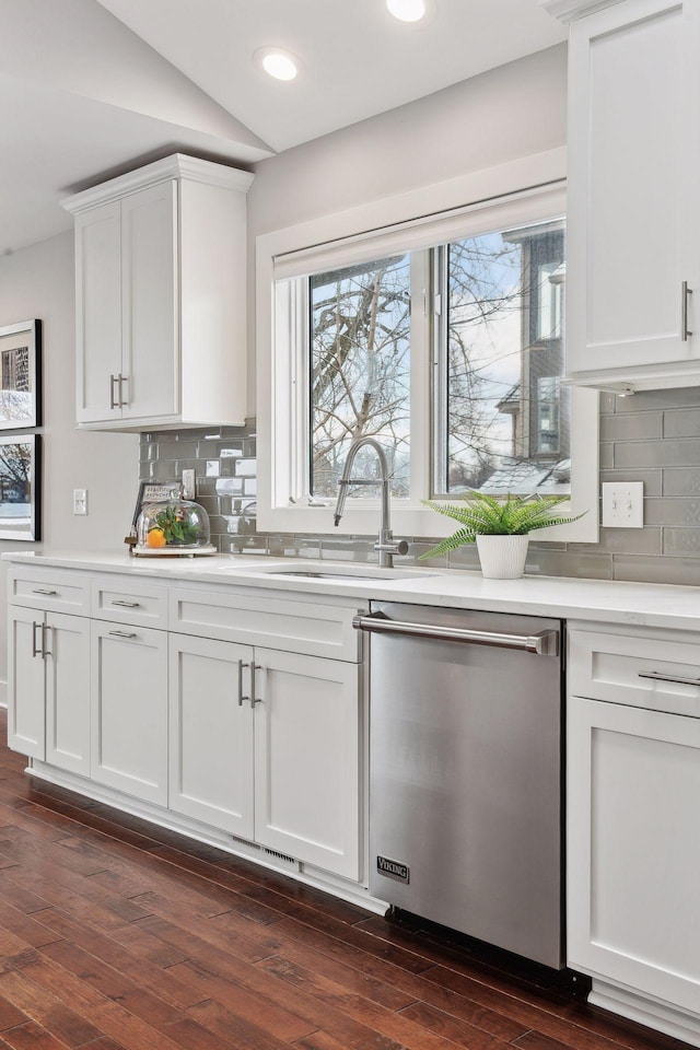 kitchen with sink, vaulted ceiling, stainless steel dishwasher, and white cabinets