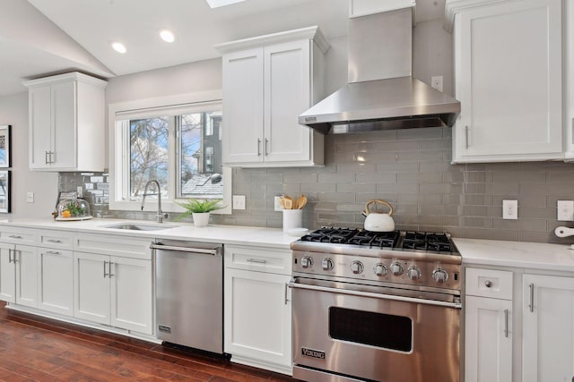 kitchen featuring white cabinetry, appliances with stainless steel finishes, wall chimney exhaust hood, and sink