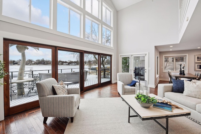 living room with plenty of natural light, wood-type flooring, and a high ceiling