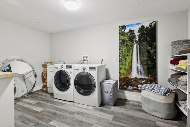 laundry area featuring washing machine and clothes dryer and light wood-type flooring