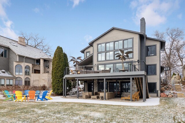 rear view of house featuring an outdoor living space with a fire pit, a patio, and a balcony