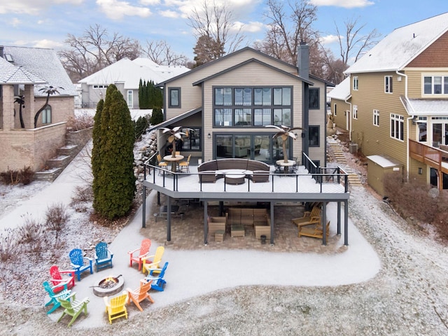 back of property with a deck and a fire pit