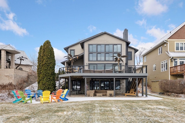 rear view of property featuring a wooden deck, an outdoor fire pit, a patio, and a lawn