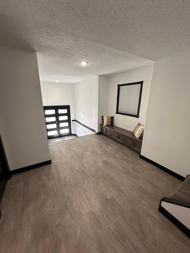 unfurnished room featuring hardwood / wood-style floors, a textured ceiling, and a baseboard heating unit