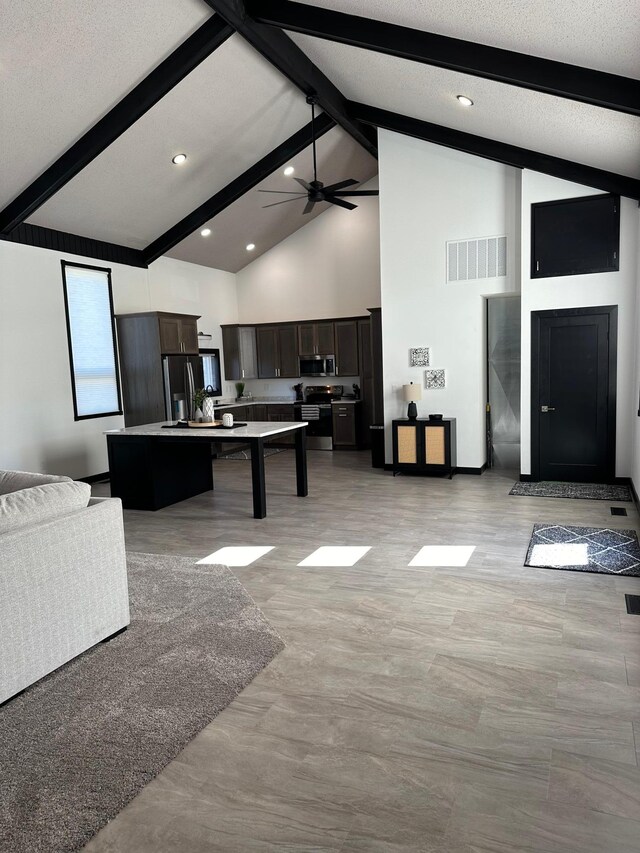 kitchen with a center island, dark brown cabinetry, high vaulted ceiling, beam ceiling, and appliances with stainless steel finishes
