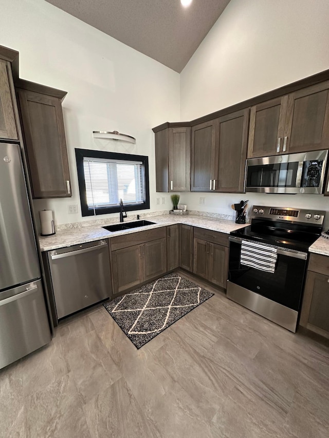 kitchen with stainless steel appliances, dark brown cabinetry, sink, a textured ceiling, and high vaulted ceiling
