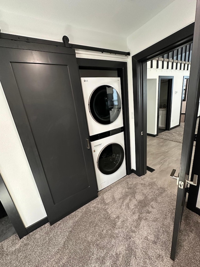washroom with a barn door, carpet flooring, and stacked washer and dryer