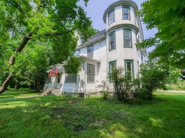 victorian home with a front yard and stucco siding