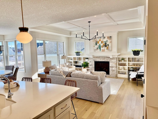 living room featuring a fireplace, coffered ceiling, light hardwood / wood-style flooring, and a textured ceiling