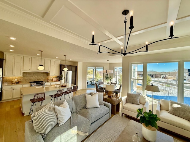 living room featuring coffered ceiling, sink, a water view, beamed ceiling, and light hardwood / wood-style floors