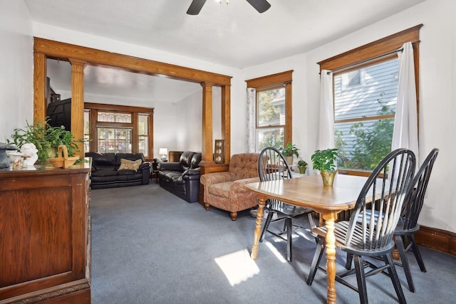 carpeted dining room featuring ceiling fan and ornate columns