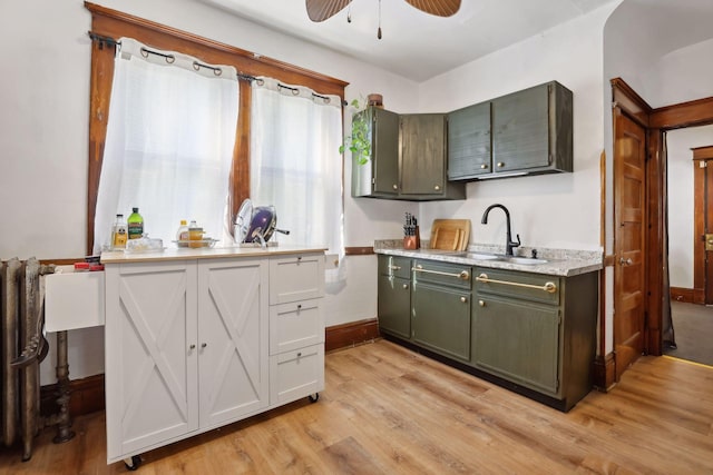 kitchen featuring sink, light hardwood / wood-style flooring, radiator, and ceiling fan