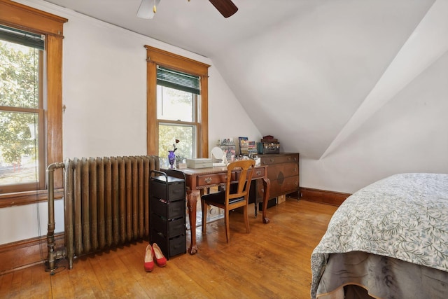 bedroom with wood-type flooring, vaulted ceiling, radiator heating unit, and ceiling fan