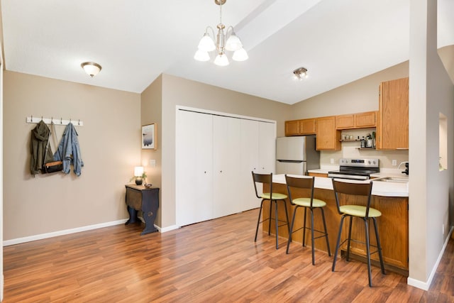 kitchen with a kitchen bar, light wood-type flooring, decorative light fixtures, and appliances with stainless steel finishes