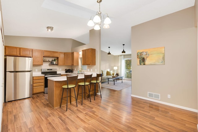 kitchen featuring a kitchen breakfast bar, stainless steel appliances, decorative light fixtures, and light wood-type flooring