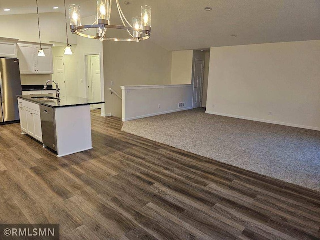 kitchen with white cabinetry, sink, stainless steel appliances, hanging light fixtures, and vaulted ceiling