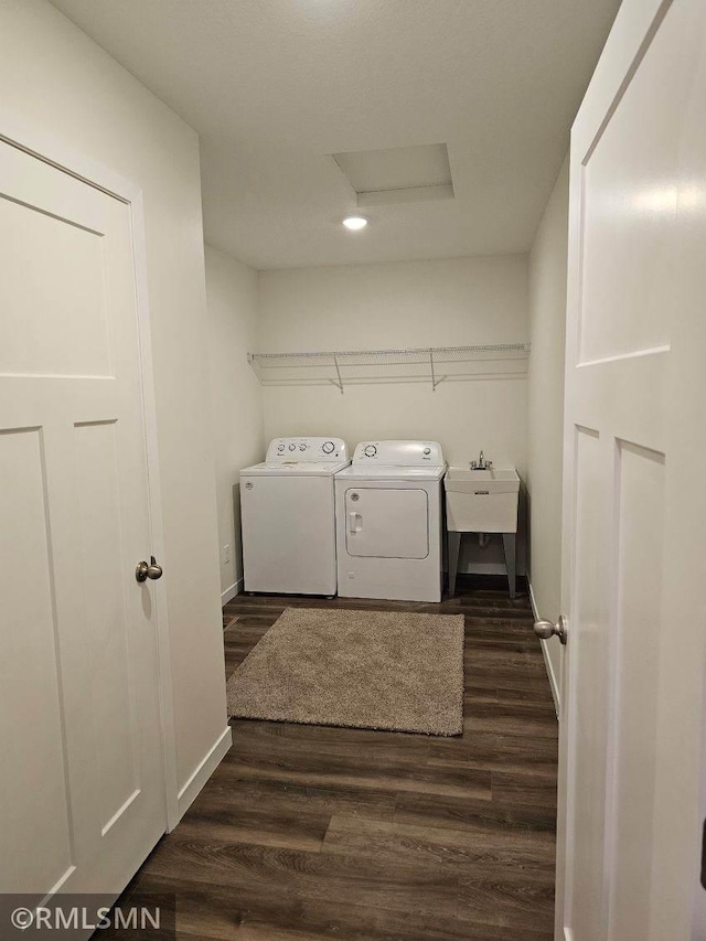 clothes washing area with sink, washer and dryer, and dark hardwood / wood-style floors