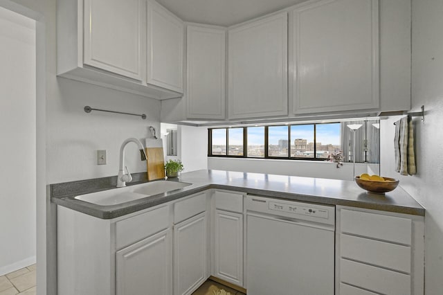 kitchen featuring kitchen peninsula, white dishwasher, sink, light tile patterned floors, and white cabinets