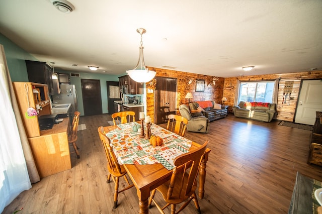 dining space with brick wall and dark hardwood / wood-style floors