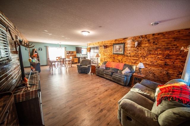 living room featuring wood-type flooring, a textured ceiling, and wood walls