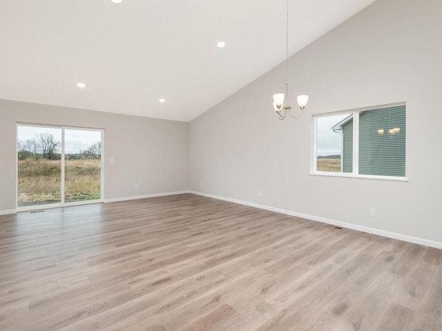 unfurnished room with high vaulted ceiling, a chandelier, and light hardwood / wood-style flooring