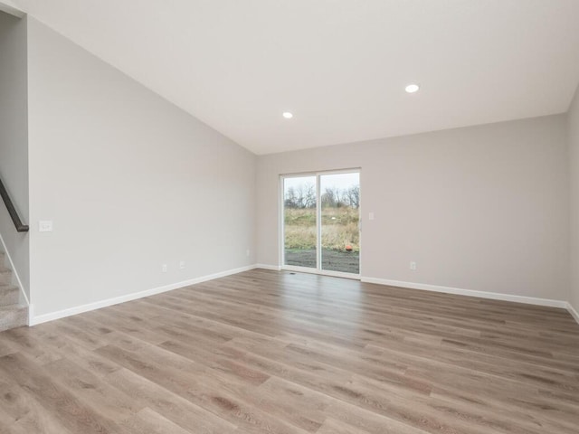 spare room with light hardwood / wood-style floors and vaulted ceiling