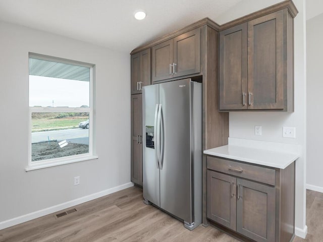 kitchen featuring dark brown cabinets, stainless steel fridge with ice dispenser, and light hardwood / wood-style flooring