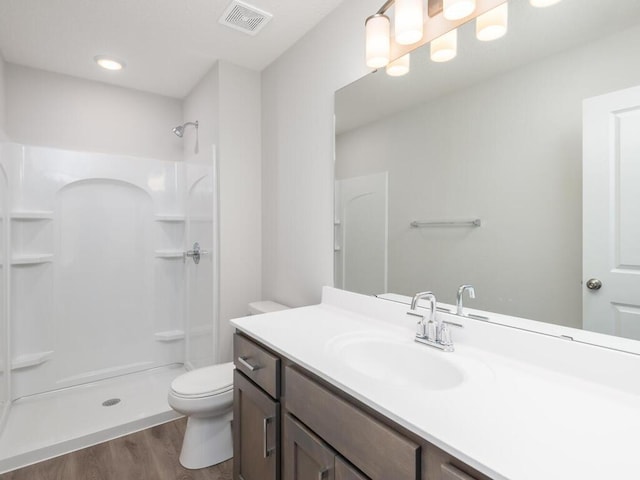 bathroom featuring vanity, hardwood / wood-style flooring, toilet, and a shower