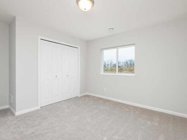 unfurnished bedroom with a closet and light colored carpet