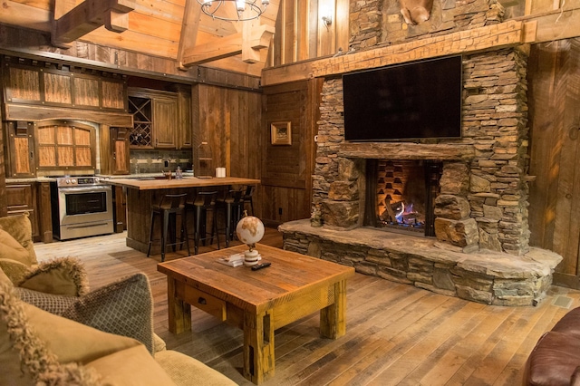 living room featuring wooden walls, wood ceiling, light wood-type flooring, and beam ceiling