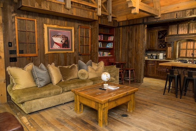 living room with built in features, wood walls, light wood-type flooring, and beam ceiling