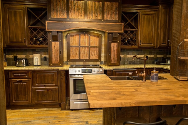 kitchen with light wood-type flooring, light stone countertops, sink, and electric range