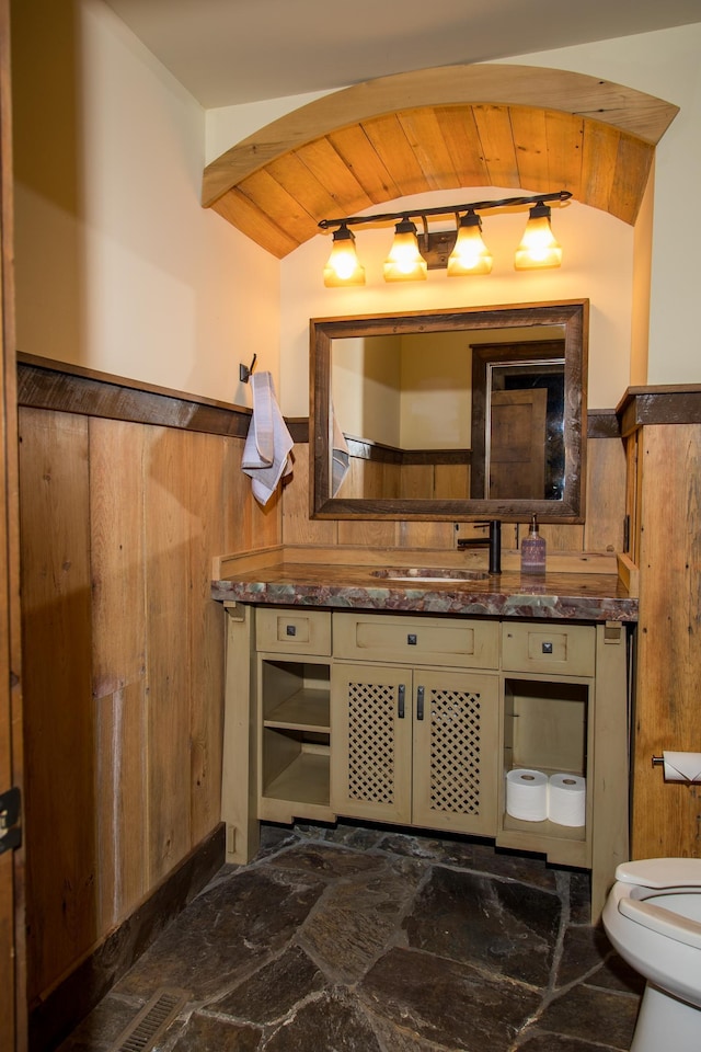33816 County Road 3, Crosslake, MN 56442 - bathroom with toilet, vanity, stone finish flooring, wooden ceiling, and wainscoting