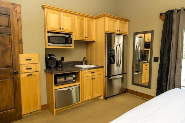 kitchen with appliances with stainless steel finishes, sink, and light carpet