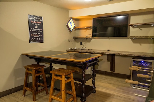 bar with beverage cooler and light hardwood / wood-style flooring